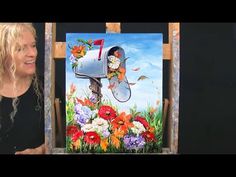 a woman standing next to a painting of a mailbox with flowers and butterflies on it