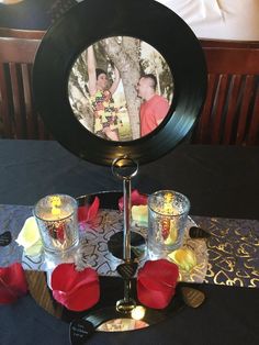 a table topped with two cups and a mirror on top of it next to candles