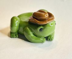 a green frog with a hat on its back