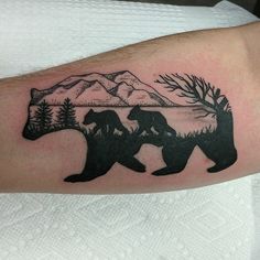 a bear and cub tattoo on the left arm, with mountains in the back ground