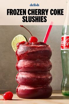 frozen cherry coke slushies in a tall glass next to a bottle of soda