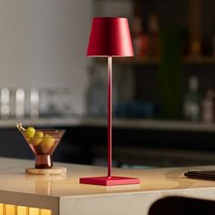 a red lamp sitting on top of a table next to a bowl filled with fruit