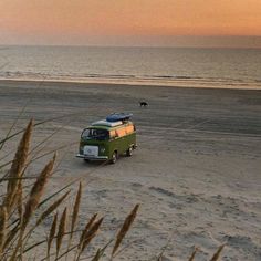 an old vw bus parked on the beach at sunset