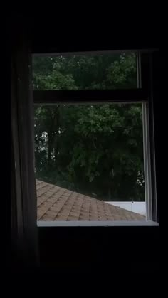 an open window in a dark room with trees outside