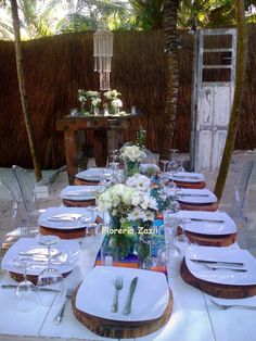 a table set with plates and silverware for an outdoor dinner party in the shade