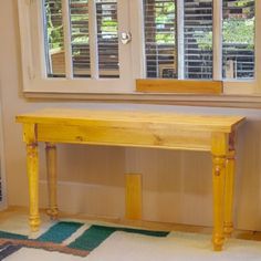 a wooden table sitting in front of two windows