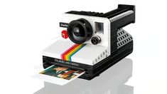 an old polaroid camera sitting on top of a piece of paper with a rainbow strip sticking out of it