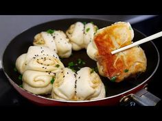 some dumplings in a pan with chopsticks sticking out of them and being cooked