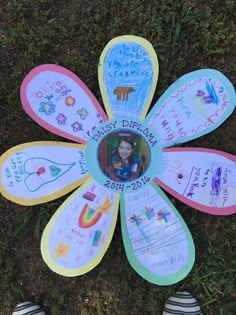 a person's feet standing in front of a flower made out of colored paper