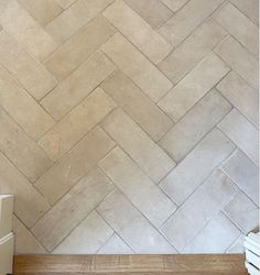 a white toilet sitting next to a wooden floor in front of a wall with herringbone pattern on it