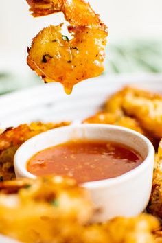 a person dipping sauce onto some fried food