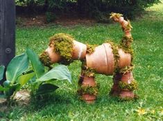 a planter made to look like a dog is in the grass next to a pole