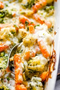 a casserole dish with broccoli, carrots and cheese on it