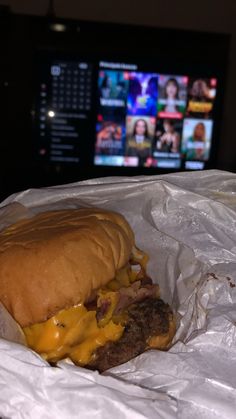 a cheeseburger with meat and melted cheese in front of a television