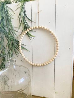 a white beaded necklace hangs on a wall next to a glass jar with water