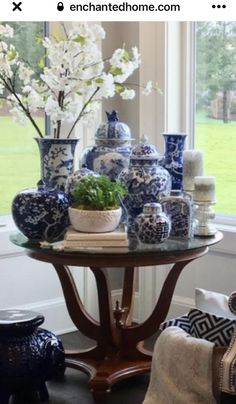 a table with vases and flowers on it in front of a window