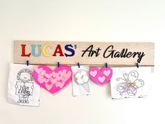 a wooden sign that says lucas'art gallery hanging on a wall with pictures and magnets attached to it