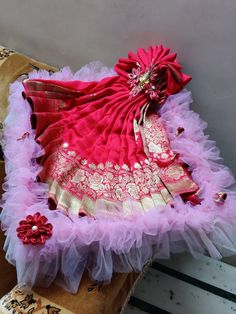 a red and pink dress sitting on top of a pillow