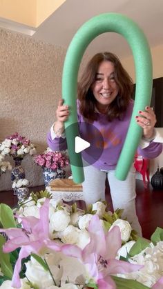 a woman holding up a large green object in front of flowers