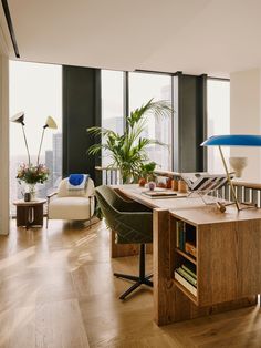 a living room filled with lots of furniture and tall windows next to a wooden floor