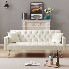 a white couch sitting on top of a hard wood floor next to a fire place