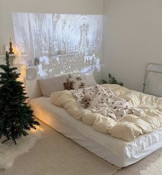 a white bed sitting next to a small christmas tree