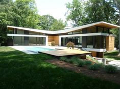 a modern house with a pool in the middle of it's lawn and trees