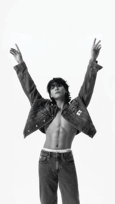 a shirtless man with his arms up in the air, wearing jeans and a jean jacket