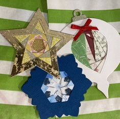 three star shaped paper ornaments on a green and white striped tablecloth