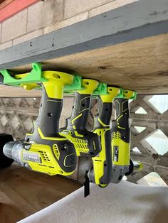 a yellow and green cordless driller hanging from the ceiling