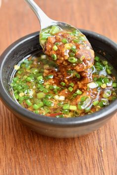 a spoon full of soup on top of a wooden table