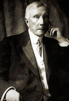 an old black and white photo of a man in a suit with his hand on his chin