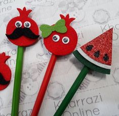 three red strawberries and one watermelon with a mustache on them, sitting next to each other