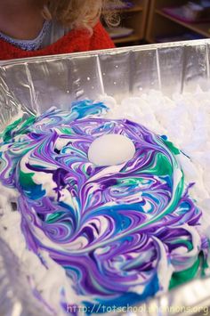 an easter egg sitting on top of a pan filled with white and blue swirled eggs