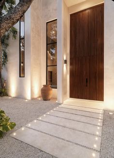 the entrance to a modern house with lights on it