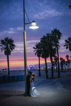 a bride and groom standing under a street light at night with palm trees in the background