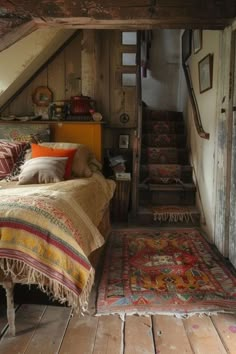 a bed sitting in the middle of a room next to a stair case and rug