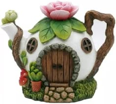 a teapot shaped like a house with a pink rose on it's roof