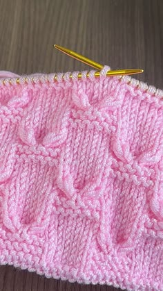 a pink knitted piece with two knitting needles