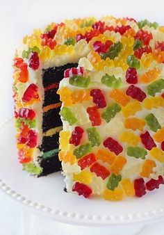 a cake with gummy bears on it is sitting on a plate and has one slice taken out