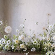 white flowers and greenery are arranged on a shelf