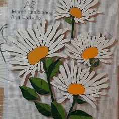 two white daisies with green leaves are on a piece of paper that has words written in it