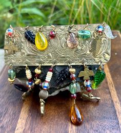 an ornate metal box with many different colored beads and charms on it's sides