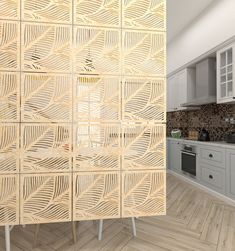 a kitchen with white cabinets and wood flooring next to a wall covered in laser cut paper