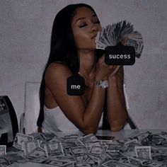 a woman sitting at a table covered in money with the words success and me written on it