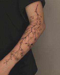 a woman's arm with flowers on it and a bird sitting on the branch