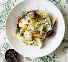 a white bowl filled with vegetables on top of a table next to glasses and spoons