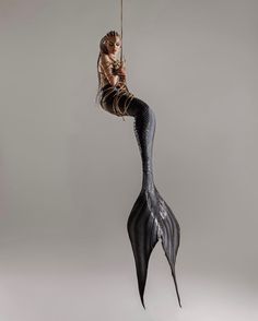 a woman with long hair is suspended from a rope in the shape of a mermaid