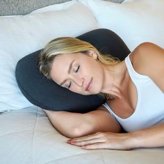 a woman laying on top of a bed with a pillow over her head and eyes closed