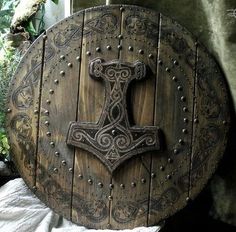 an old wooden shield with metal studs and a cross on the front is shown